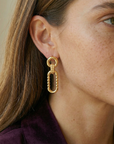 Close-up of a woman wearing gold earrings with a neutral background