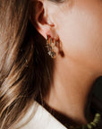 Close-up of an ear wearing gold hoop earrings with a blurred background