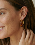 Woman wearing a tortoiseshell hoop earring with a neutral background