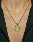 Gold necklace with a pendant on a person wearing a black shirt