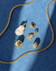 Gold jewelry set including necklace, earrings, and pendants on a blue fabric background
