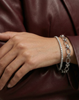 Hand wearing a silver bracelet on a person in a maroon leather jacket.