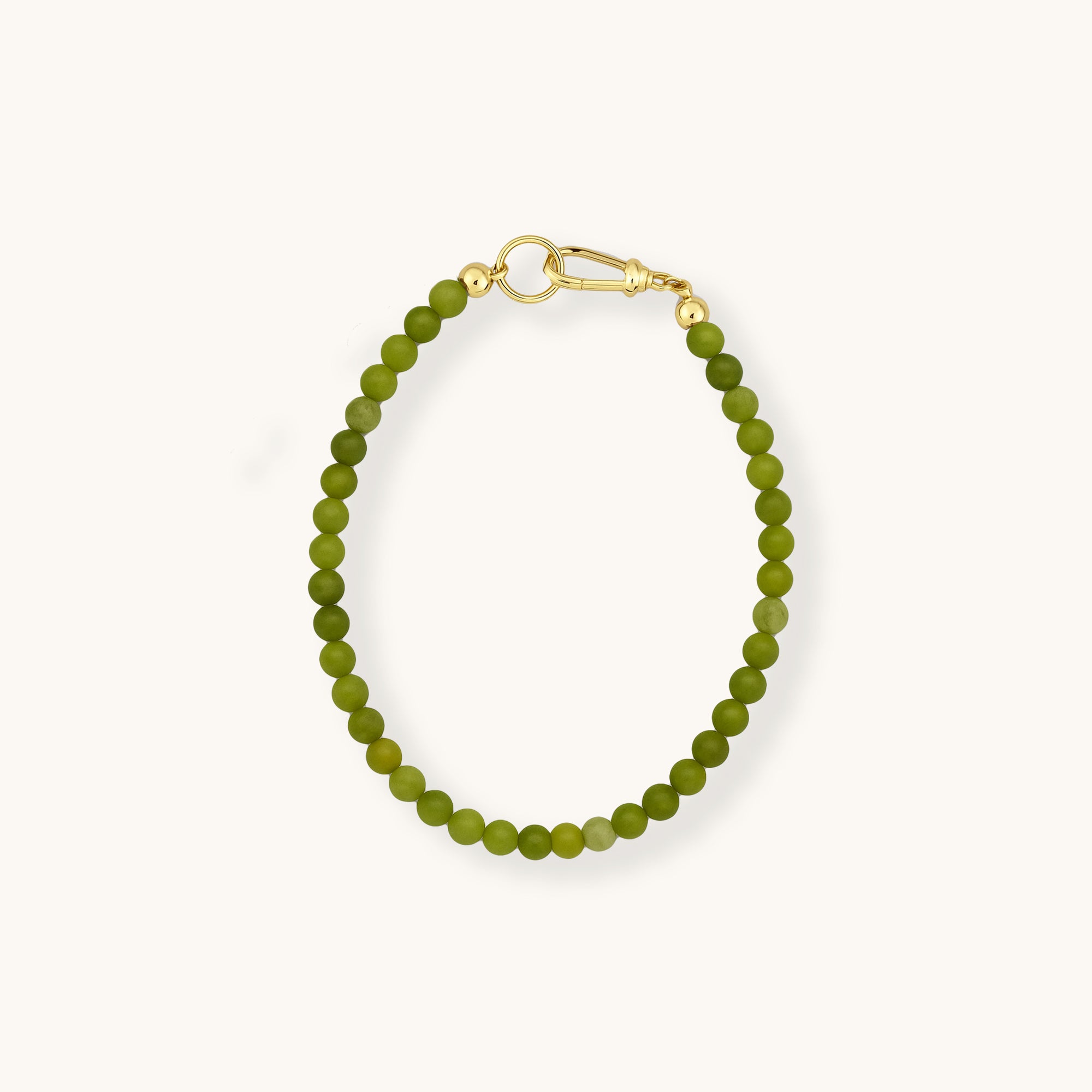 Green beaded bracelet with gold clasp on a white background