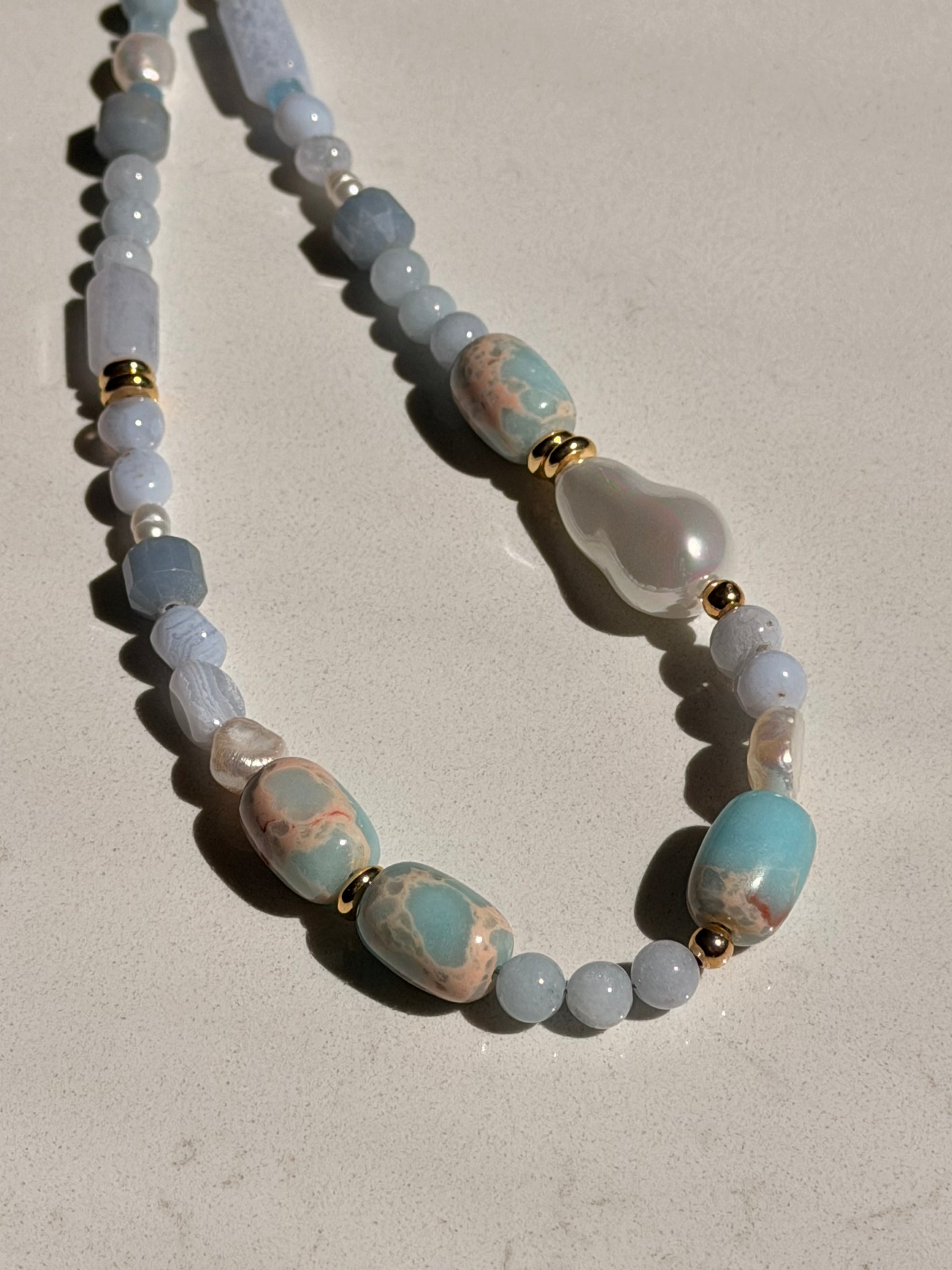 Necklace with blue and white beads on a beige background