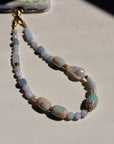 Beaded phone lanyard with pearls and gold accents on a light surface
