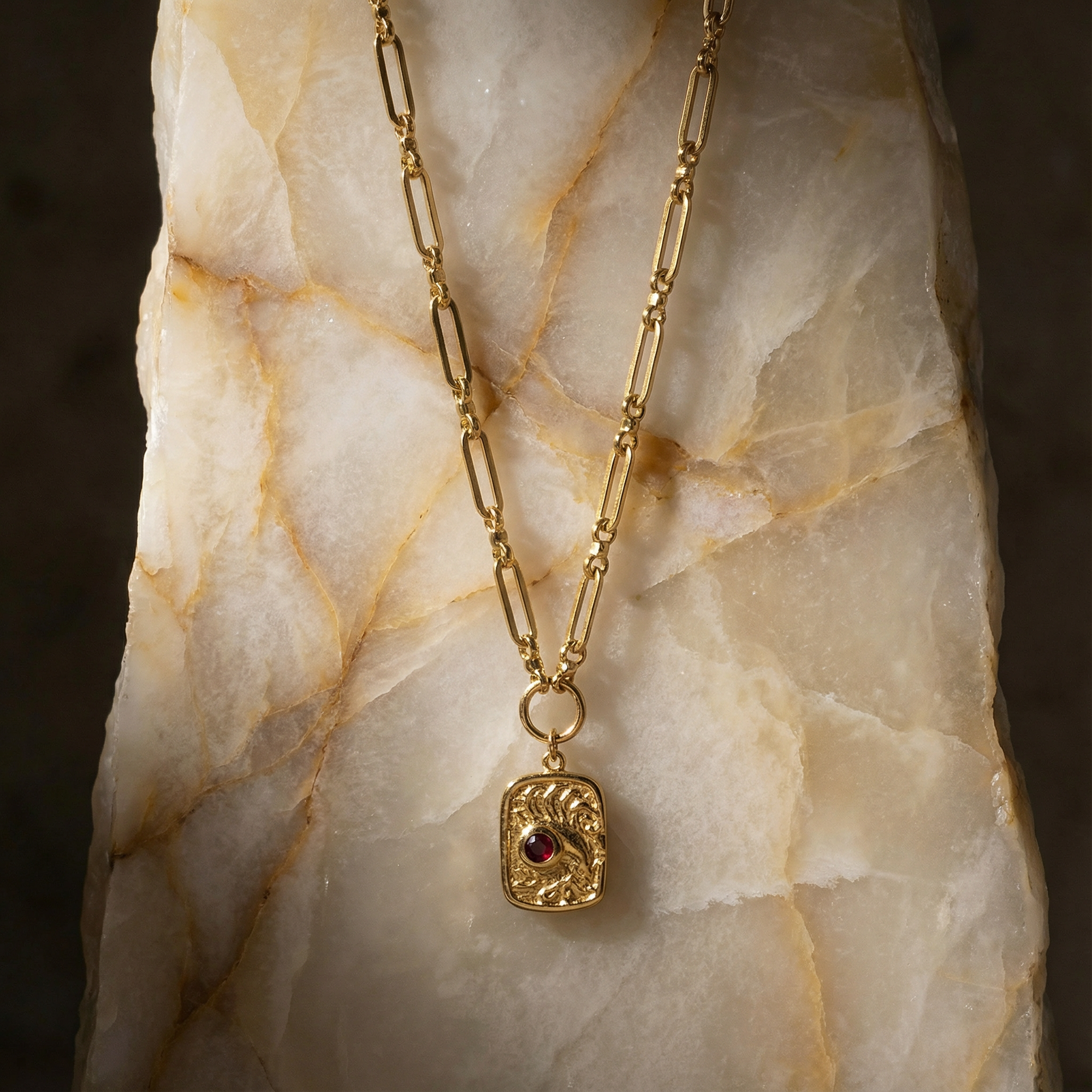 Gold necklace with a pendant on a marble surface