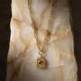 Gold necklace with a pendant on a marble surface