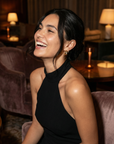 Woman in a black dress sitting in a cozy room with warm lighting