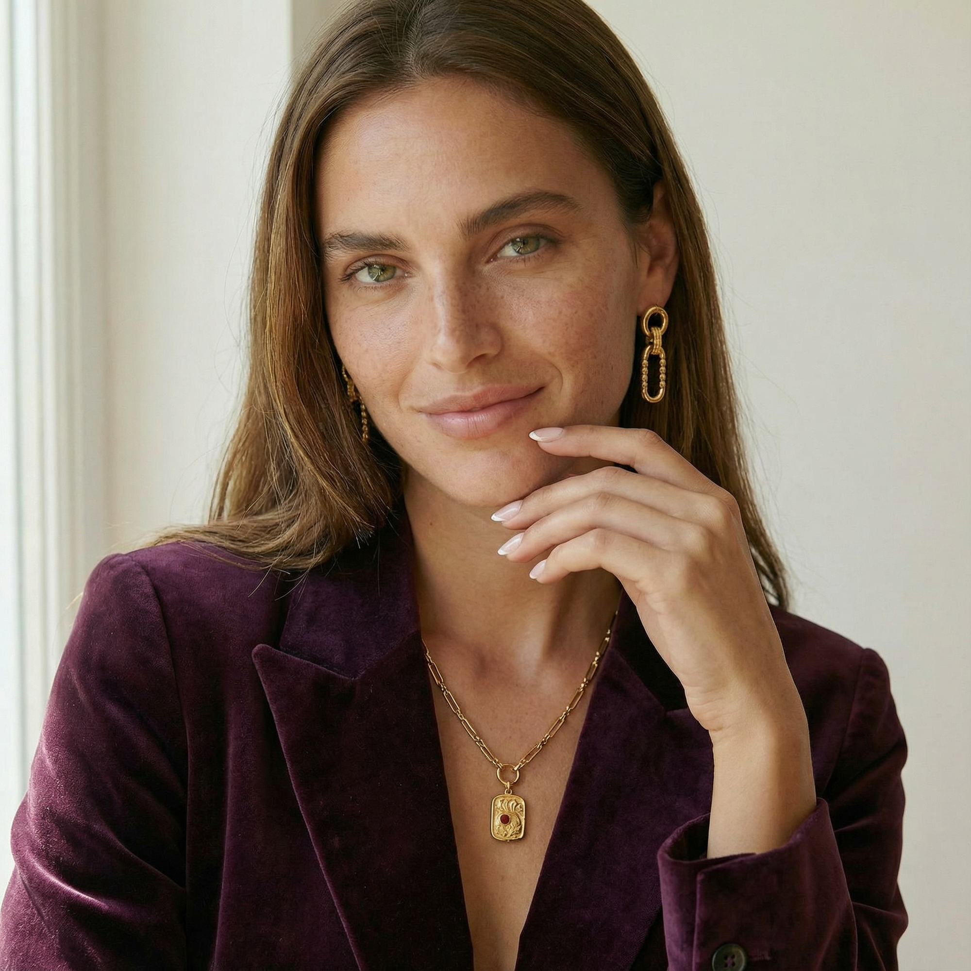 Woman wearing a purple blazer and gold jewelry indoors