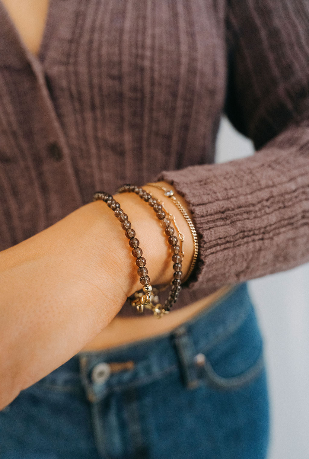 Close-up of a person wearing multiple bracelets on a wrist with a blurred background