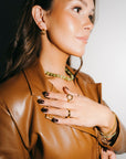 Woman wearing a brown leather jacket with jewelry, including rings and a necklace.