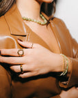 Person wearing a brown leather jacket with jewelry on a neutral background