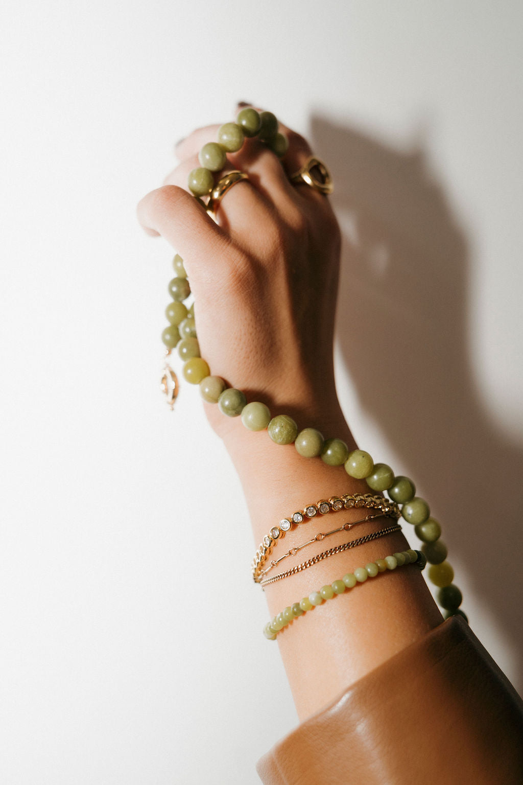 Hand wearing multiple bracelets on a plain background