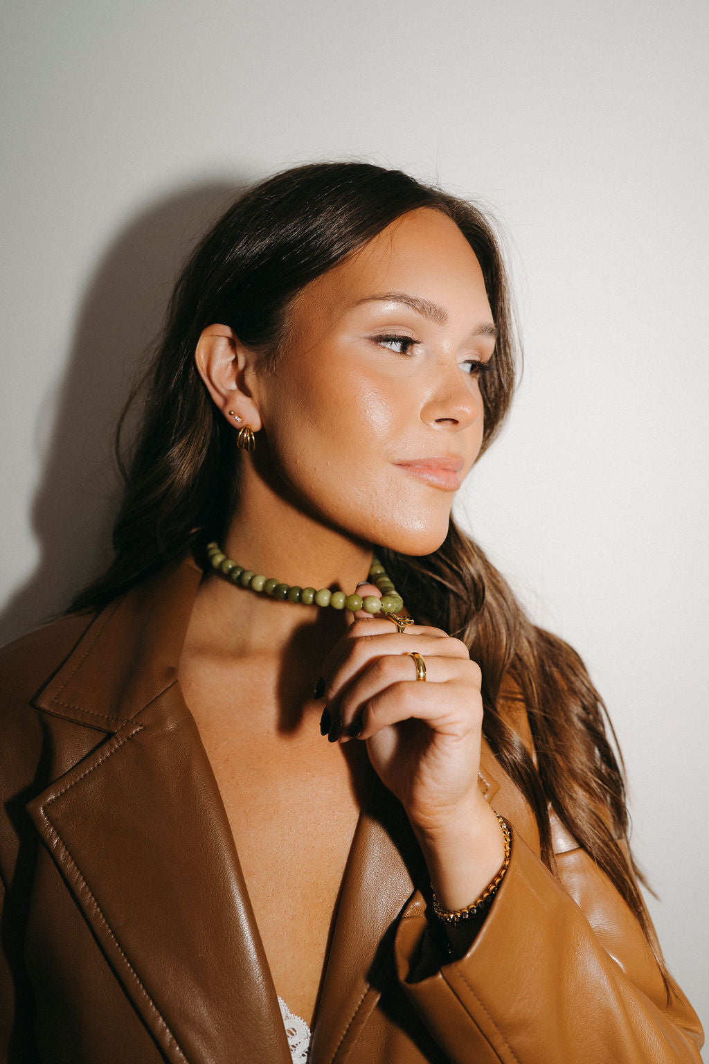 Woman wearing a brown leather jacket with a plain background