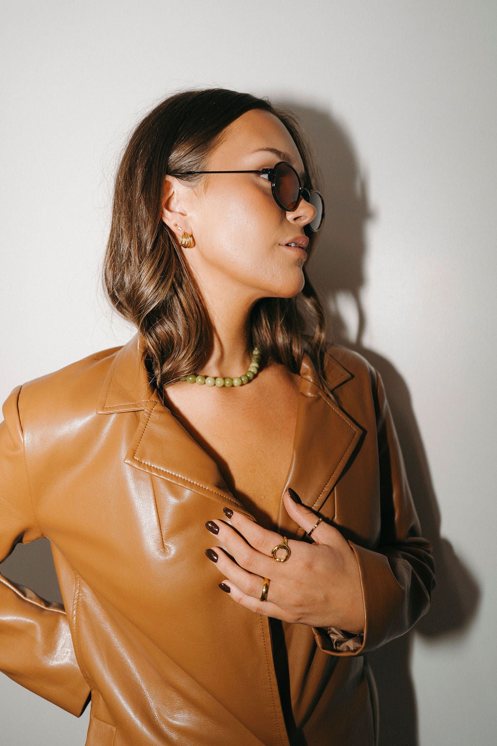 Woman wearing a brown leather jacket against a plain background