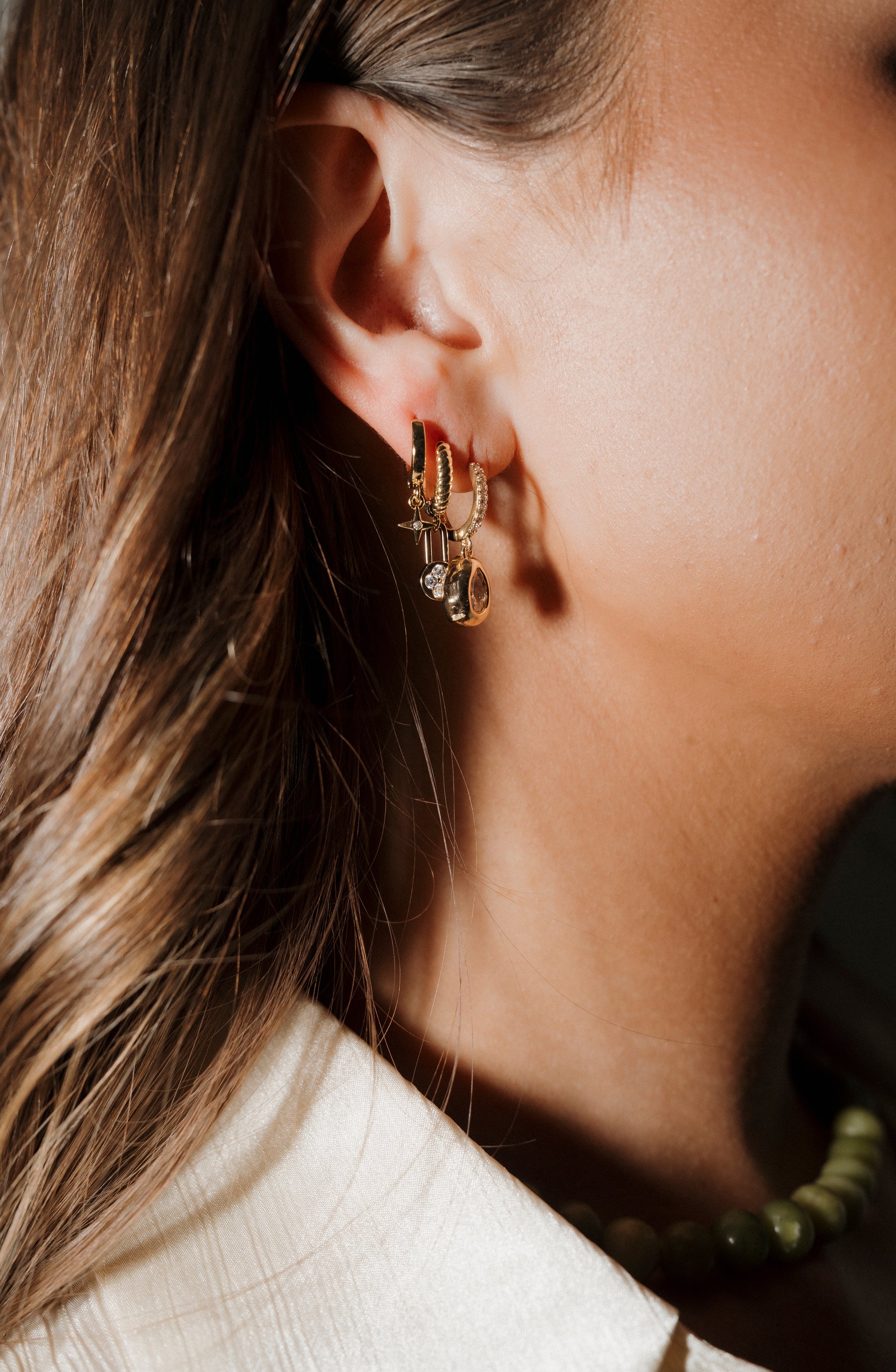 Close-up of an ear wearing a gold earring with a blurred background
