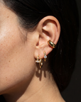 Close-up of an ear wearing gold hoop earrings with a dark background