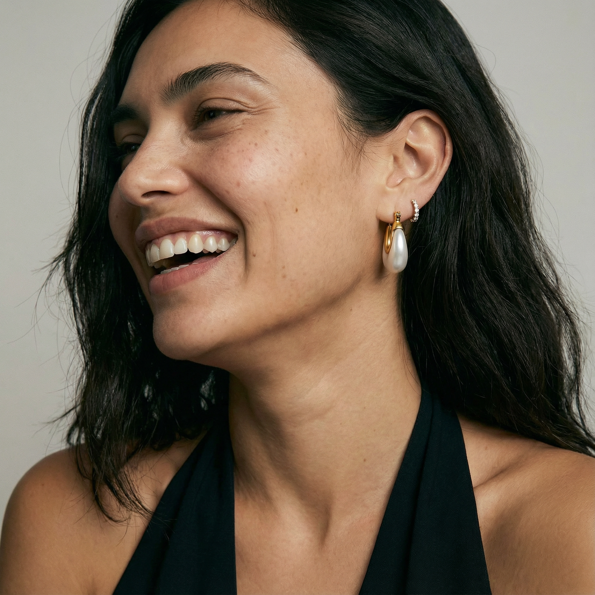 Woman wearing gold hoop earrings with a neutral background