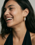 Woman wearing gold hoop earrings with a neutral background