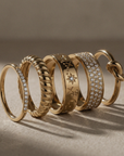 Set of gold rings with various designs on a neutral background