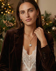 Woman in a brown blazer with Christmas decorations in the background