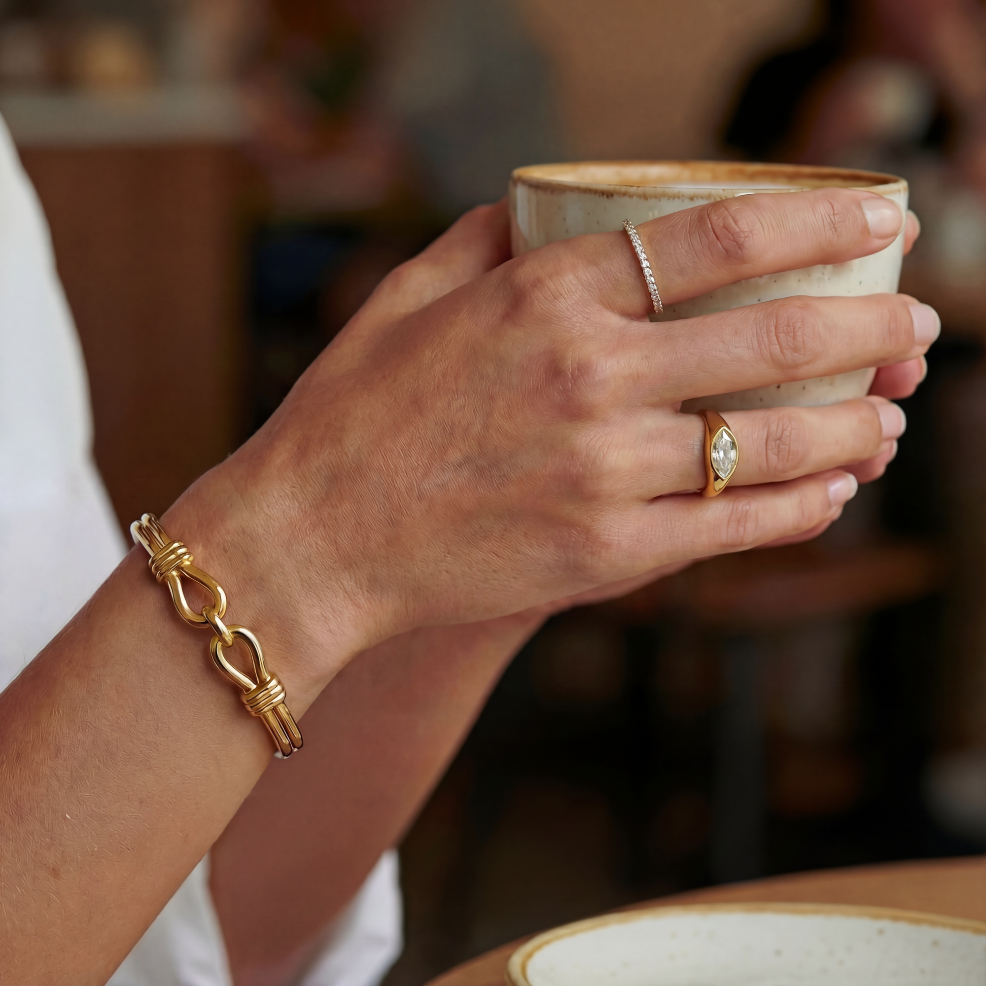 Hand holding a ceramic cup with jewelry on a blurred background