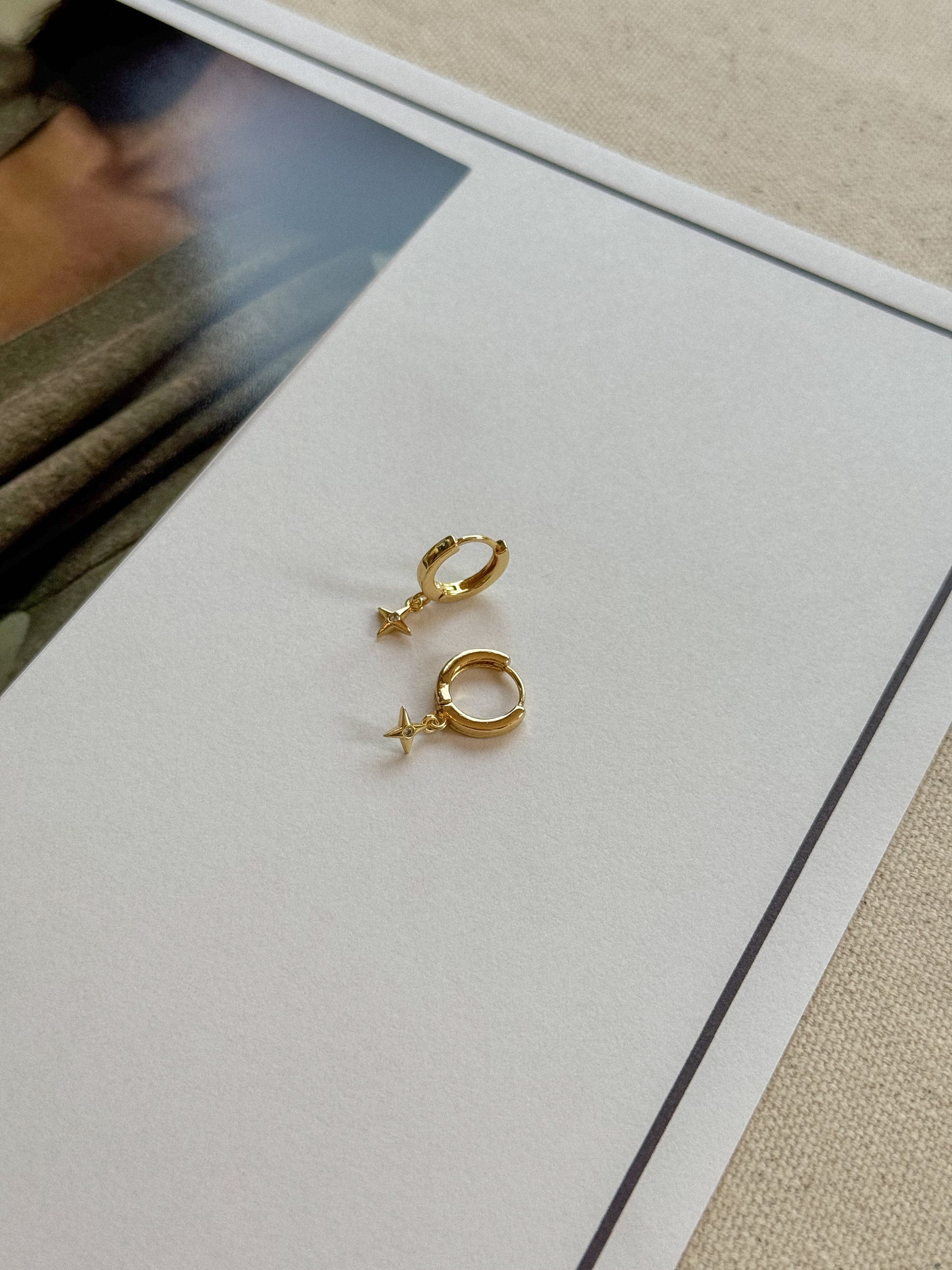 Gold hoop earrings on a white card with a blurred background