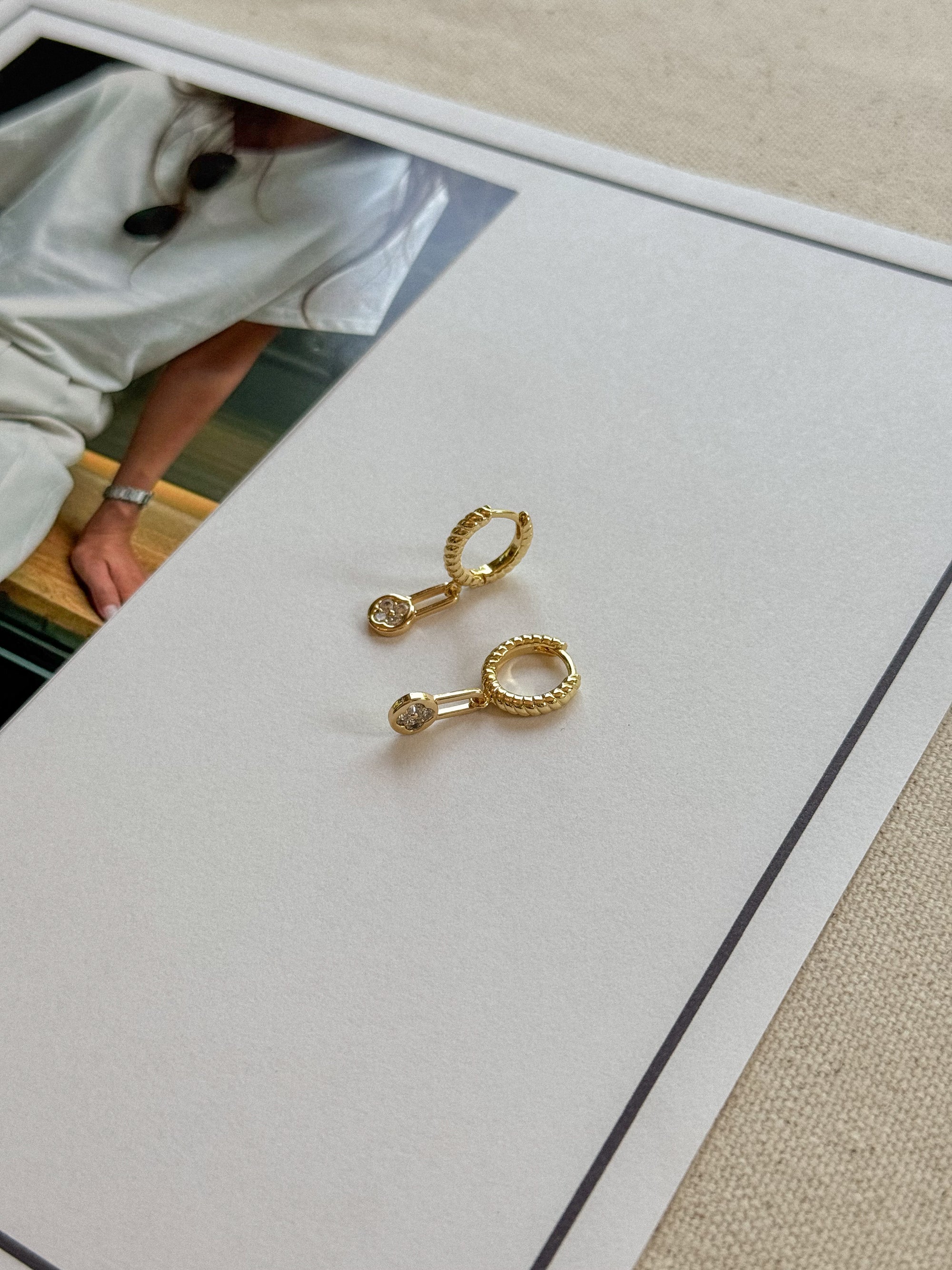 Gold hoop earrings on a white card with a blurred background