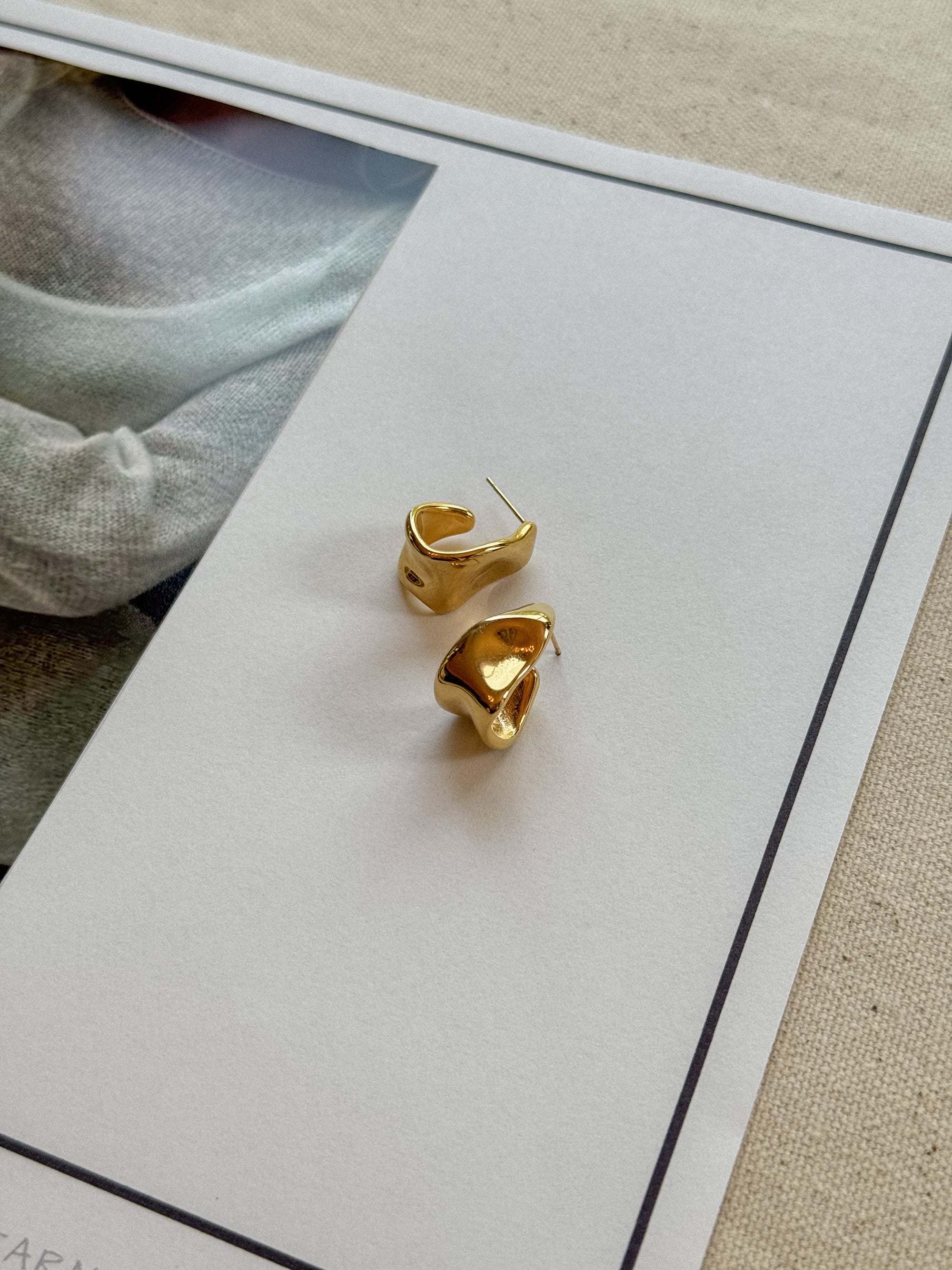 Gold hoop earrings on a white card with a blurred background