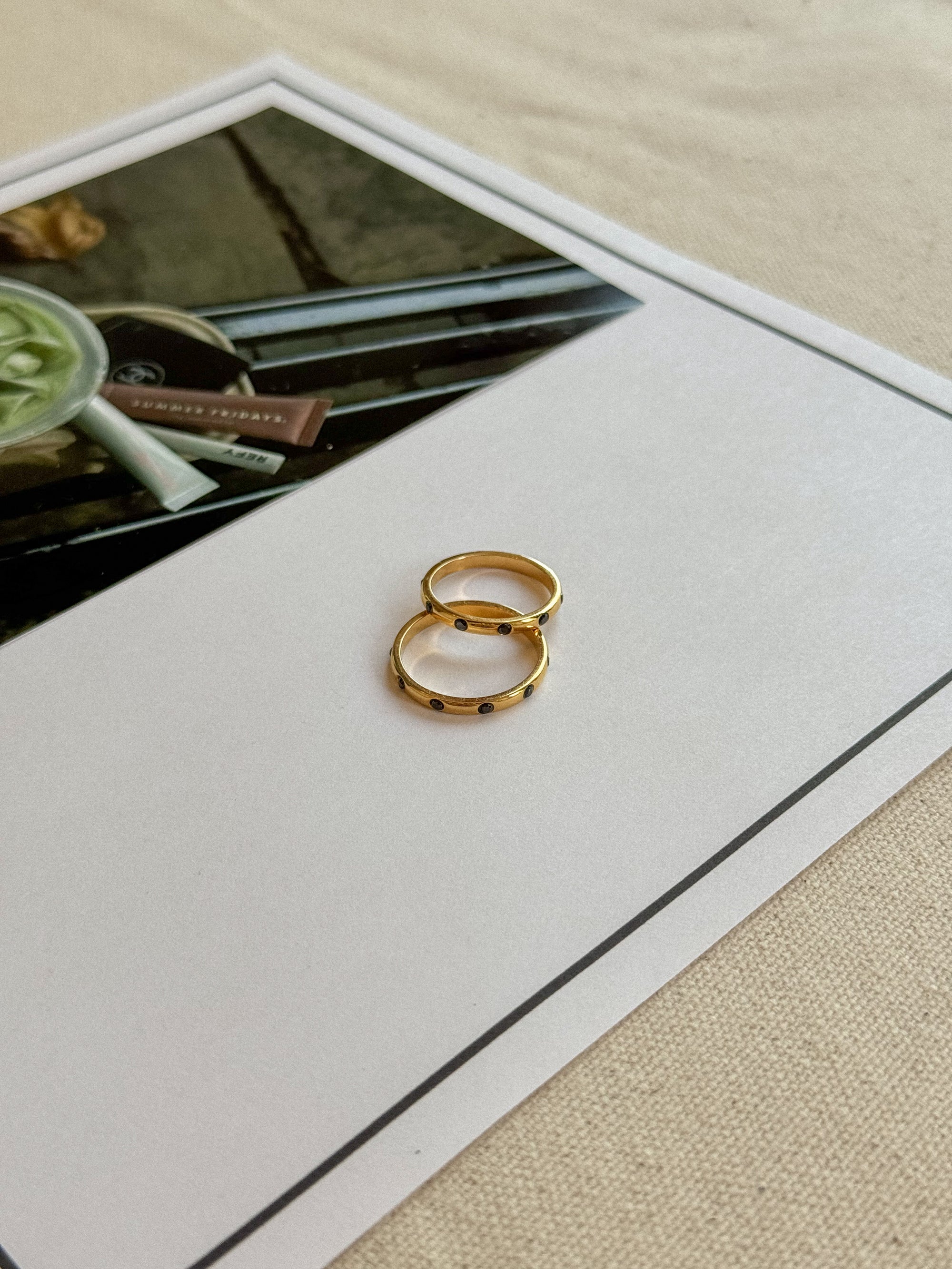 Two gold rings on a white card with a blurred background