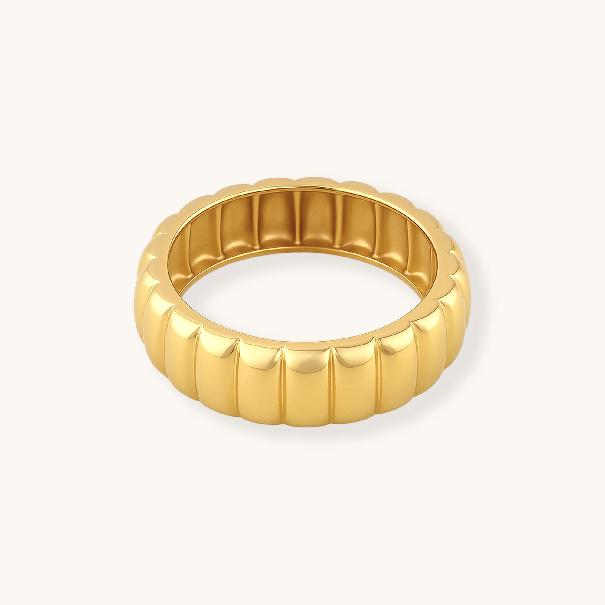 Gold ring with ribbed texture on a white background