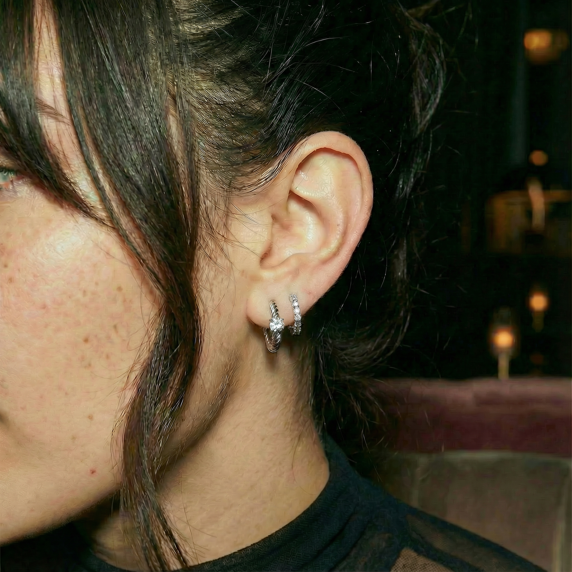 Close-up of an ear with a diamond earring in a dimly lit setting
