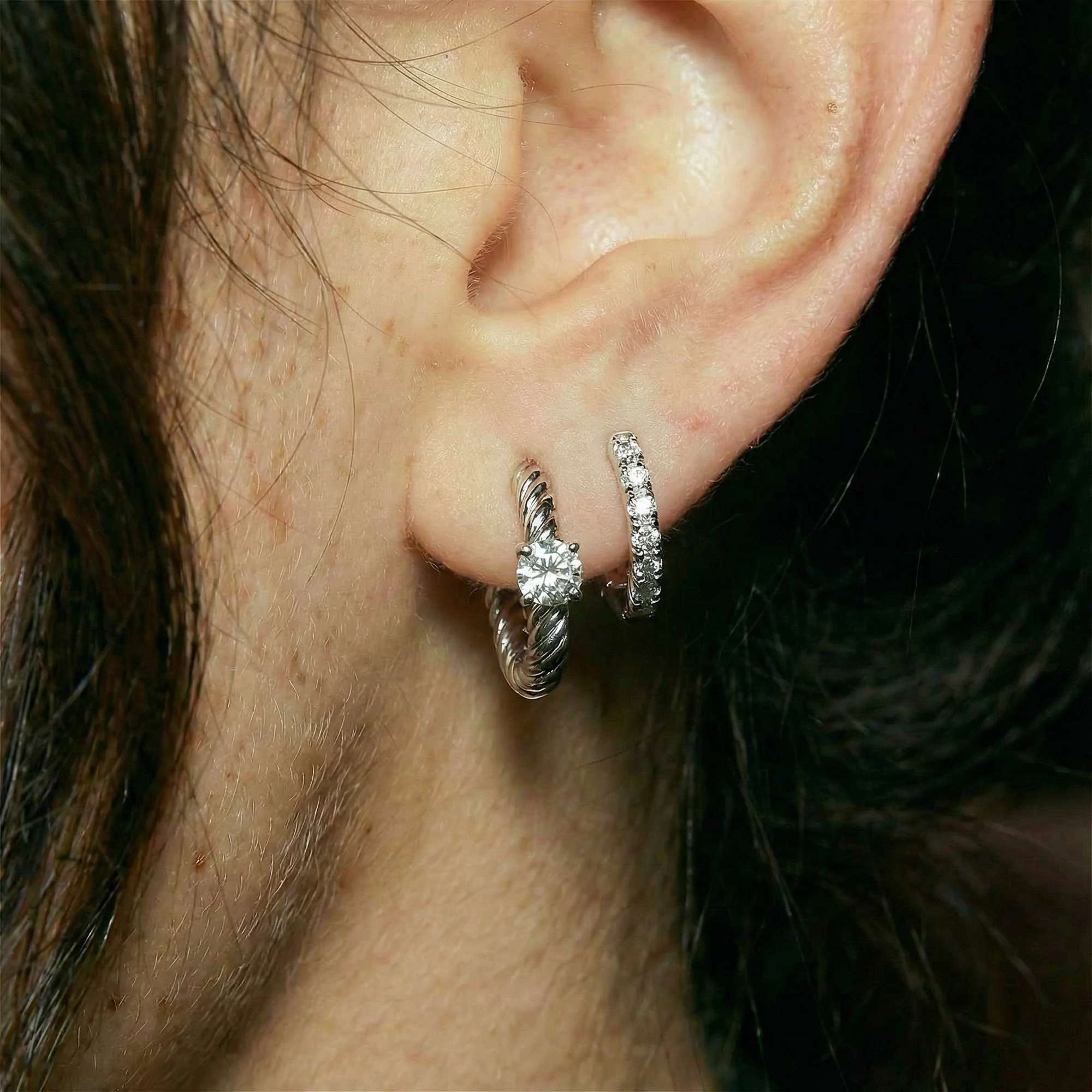 Close-up of an ear wearing two silver hoop earrings.