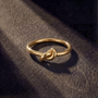 Gold ring with a knot design on a dark textured surface
