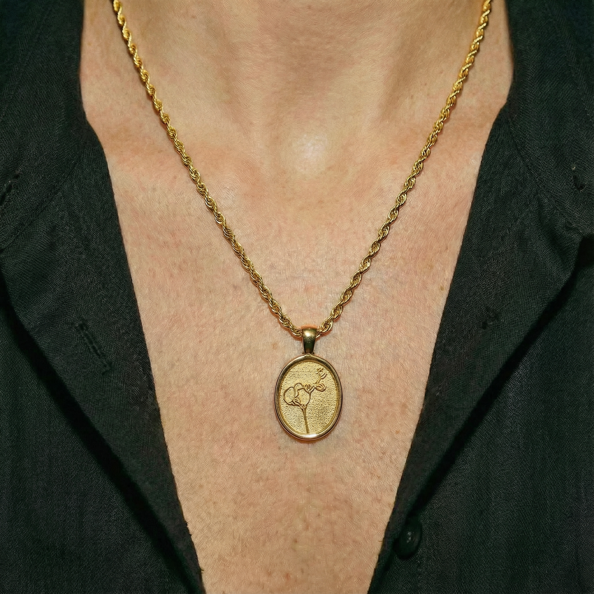 Gold necklace with a pendant on a person wearing a black shirt