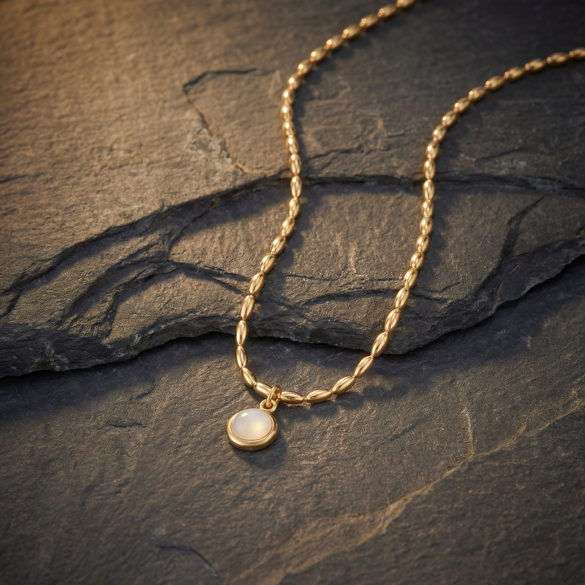 Gold necklace with a pendant on a dark stone surface