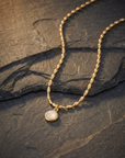 Gold necklace with a pendant on a dark stone surface