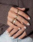 Hand with multiple gold rings on a brown sweater background