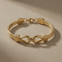 Gold bracelet with interlocking design on a beige background
