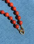 Red beaded necklace with a gold clasp on a blue fabric background
