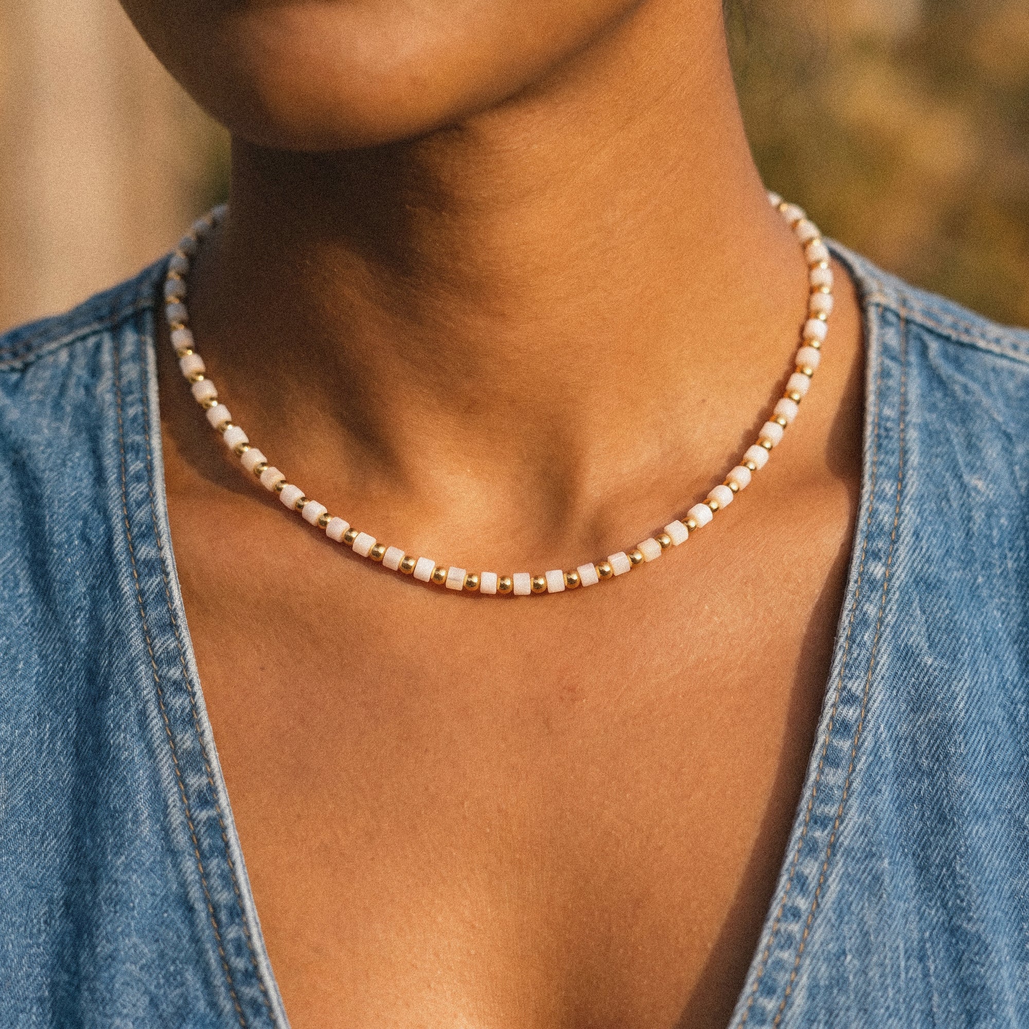 Person wearing a pearl necklace with a blurred background
