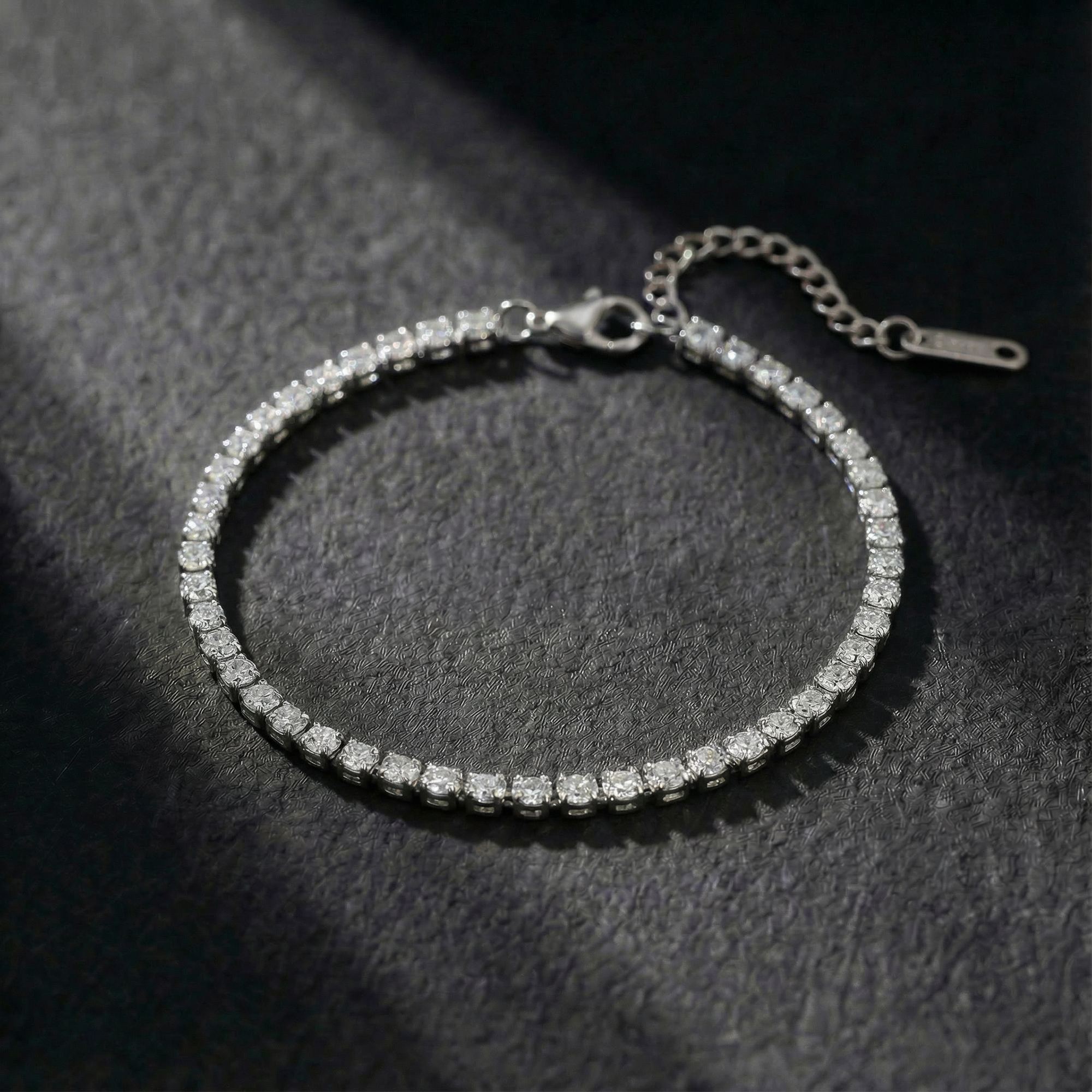 Silver bracelet with clear stones on a dark textured surface
