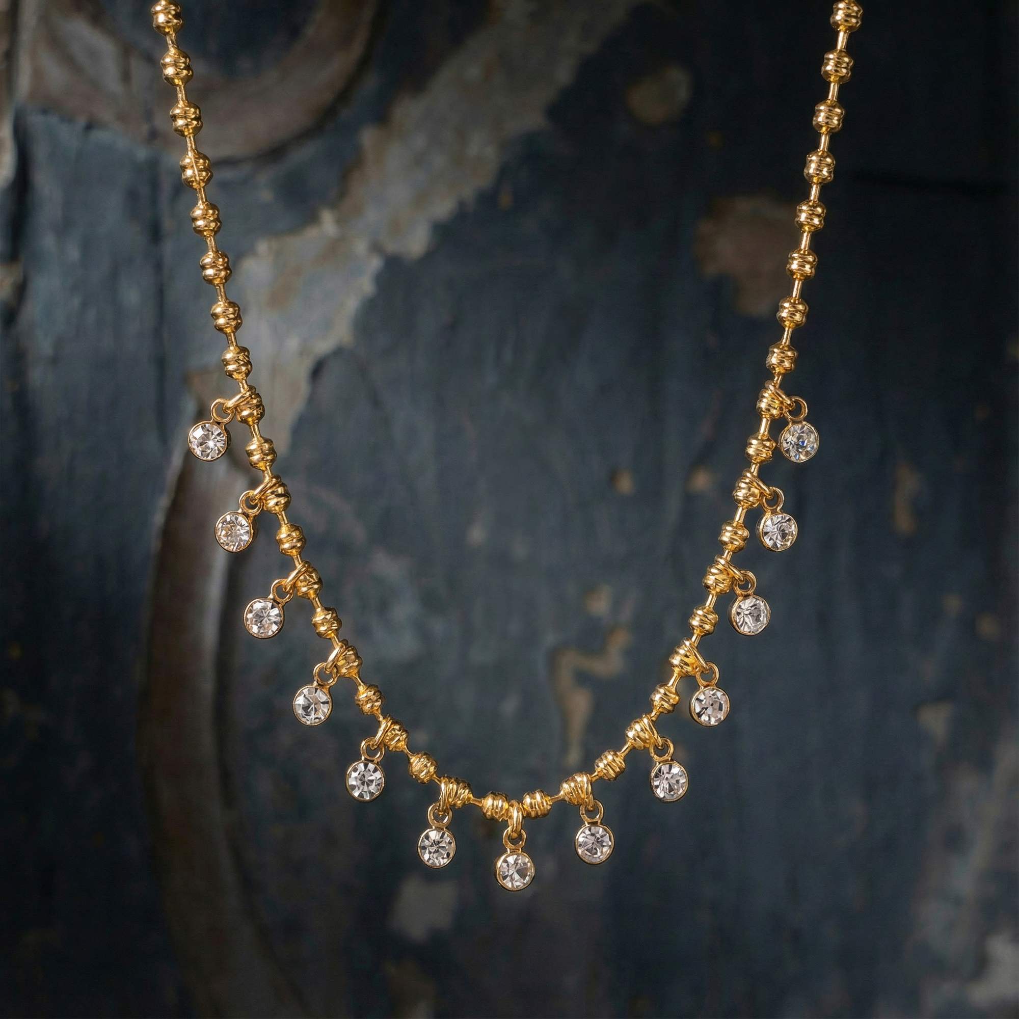 Gold necklace with crystal beads on a textured dark background