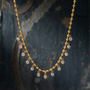 Gold necklace with crystal beads on a textured dark background