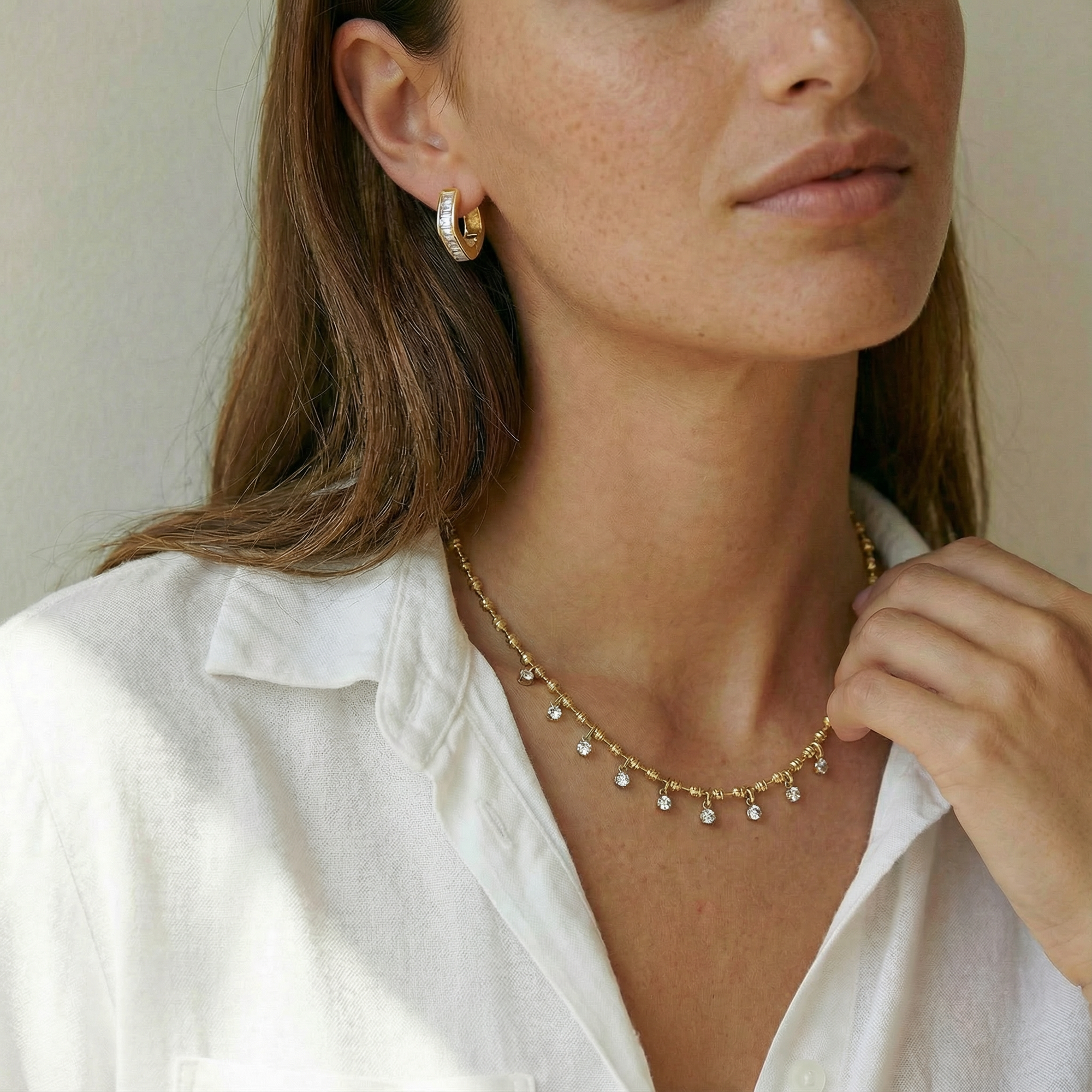 Woman wearing a gold necklace and earrings against a neutral background
