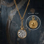 Gold pendant necklace with detailed design on a dark textured background