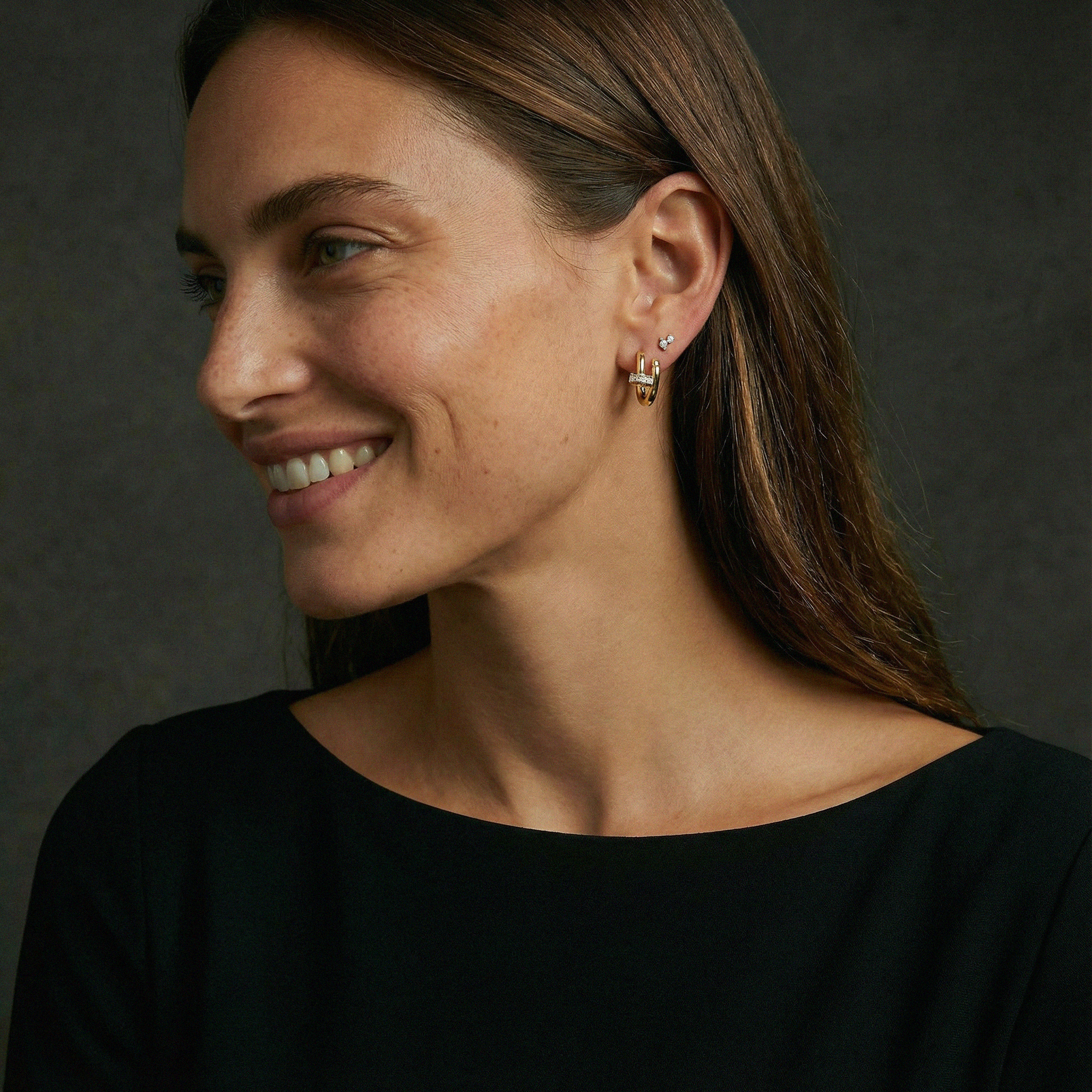 Woman wearing gold earrings against a dark background